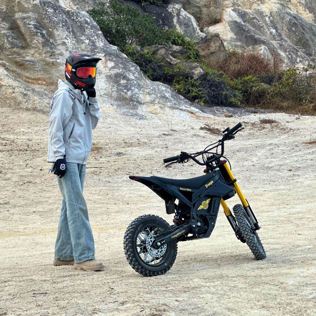 Rider standing beside a Freego Nova 5 Mini on a rocky trail
