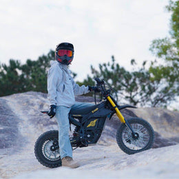 Rider in a full-face helmet beside a Nova 5 Mini on a rock face