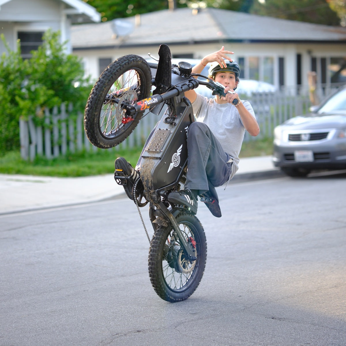 Rider in a helmet lifting the front wheel of a Freego X1 on a street