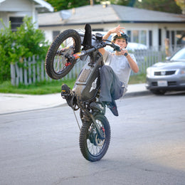 Rider in a helmet lifting the front wheel of a Freego X1 on a street